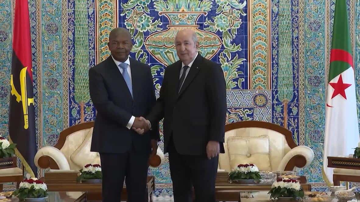 Deux dirigeants se serrent la main devant un décor coloré.