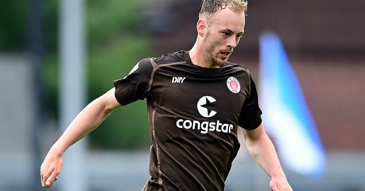 Joueur de football en mouvement sur le terrain avec maillot noir.