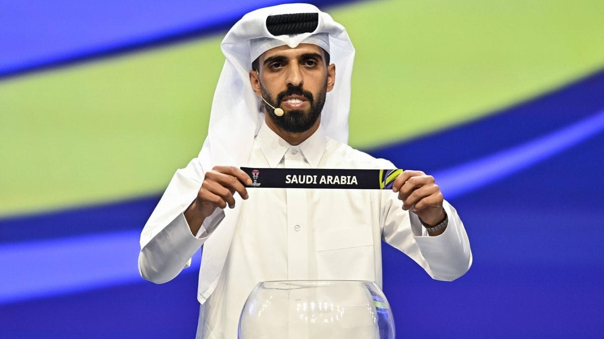 Homme en tenue traditionnelle saoudienne tenant un badge avec 'Saudi Arabia'.