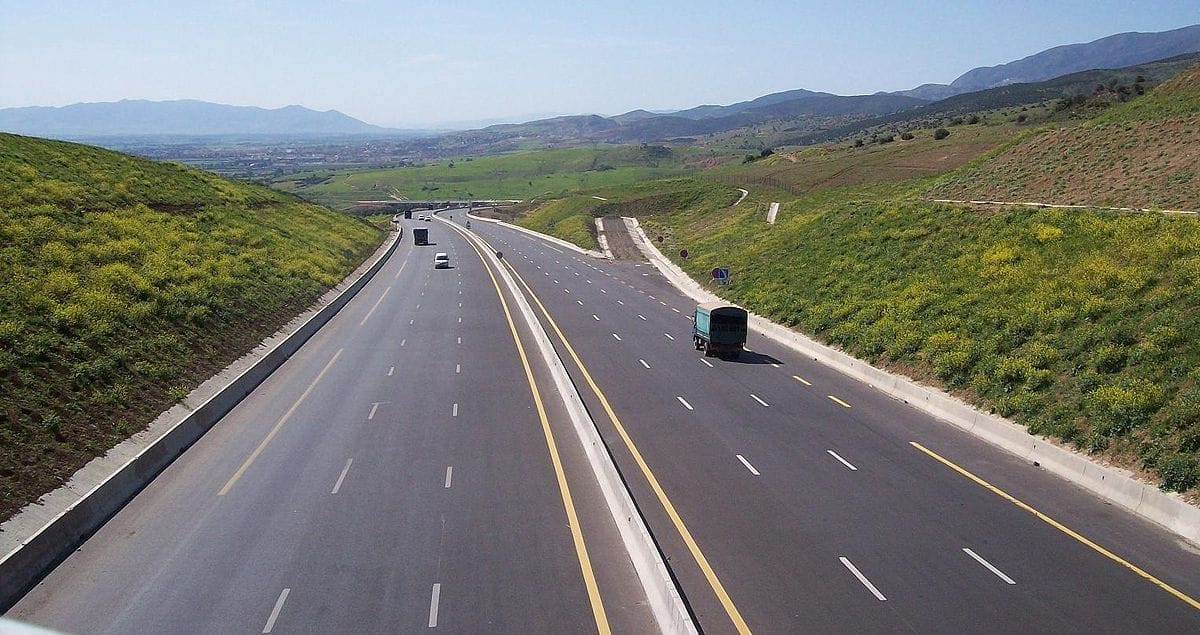 Autoroute en Algérie avec paysages montagneux et verdoyants.