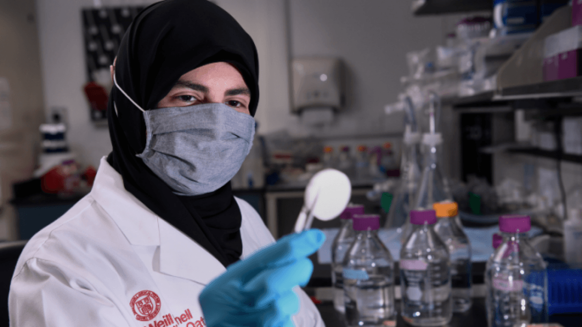 Chercheuse en laboratoire avec pipette et équipements scientifiques.
