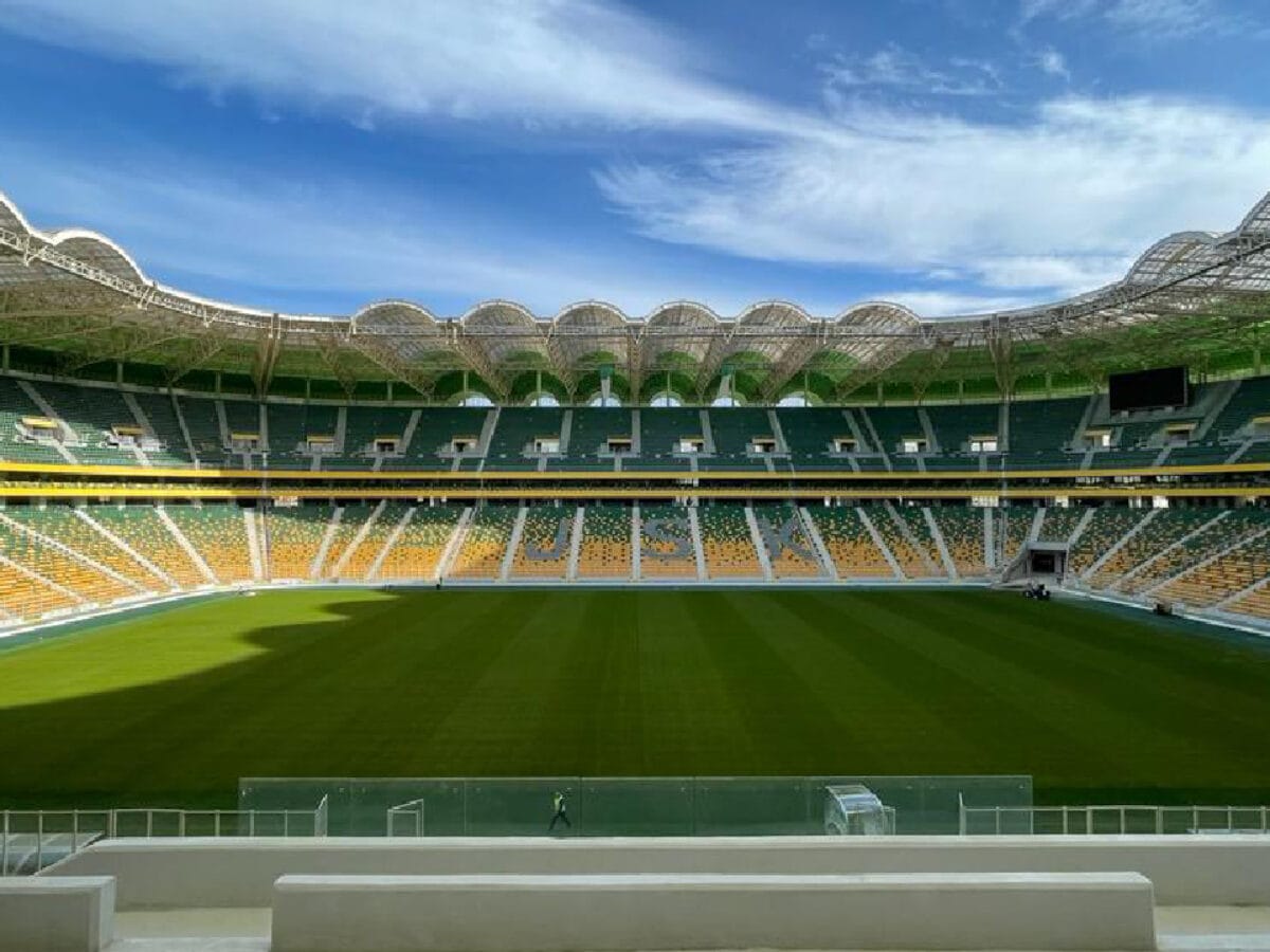 Stade de football vide avec ciel bleu et nuages.