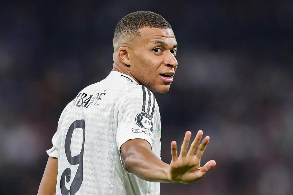 Kylian Mbappé portant le maillot de football blanc, en mouvement sur le terrain.