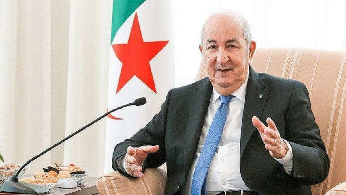 Président Tebboune en réunion avec drapeau algérien en arrière-plan.