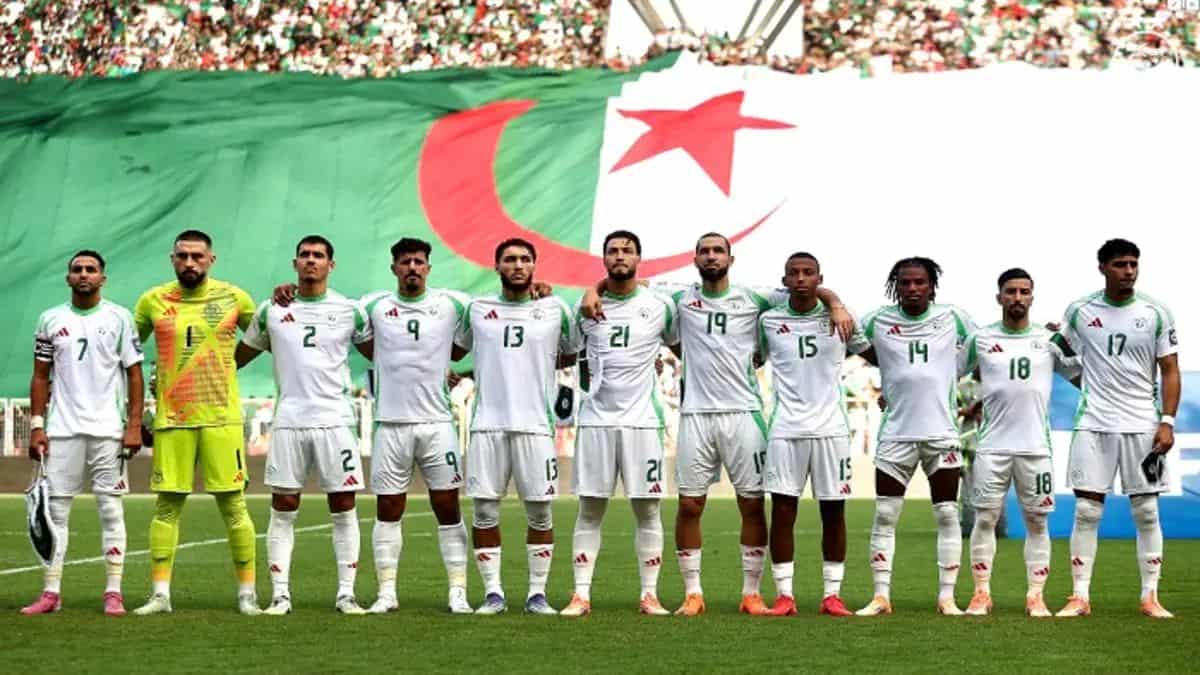 Les joueurs algériens alignés devant un drapeau national lors d'un match.