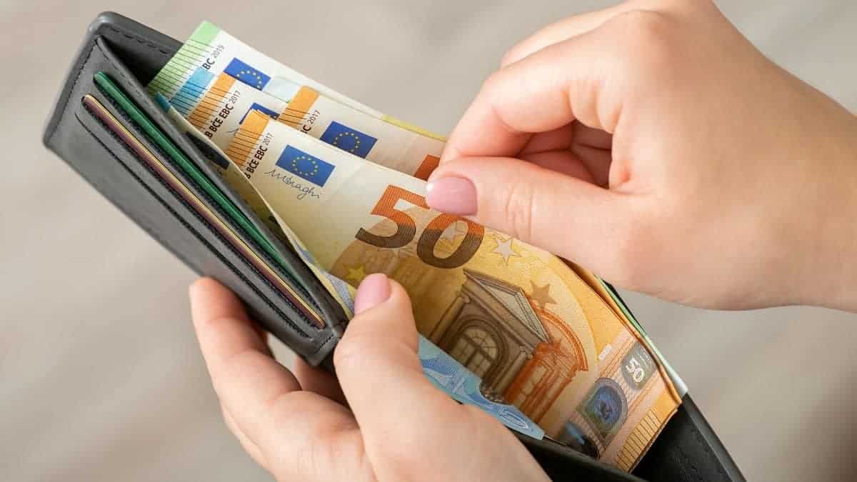 Main tenant un portefeuille rempli de billets de 50 euros.