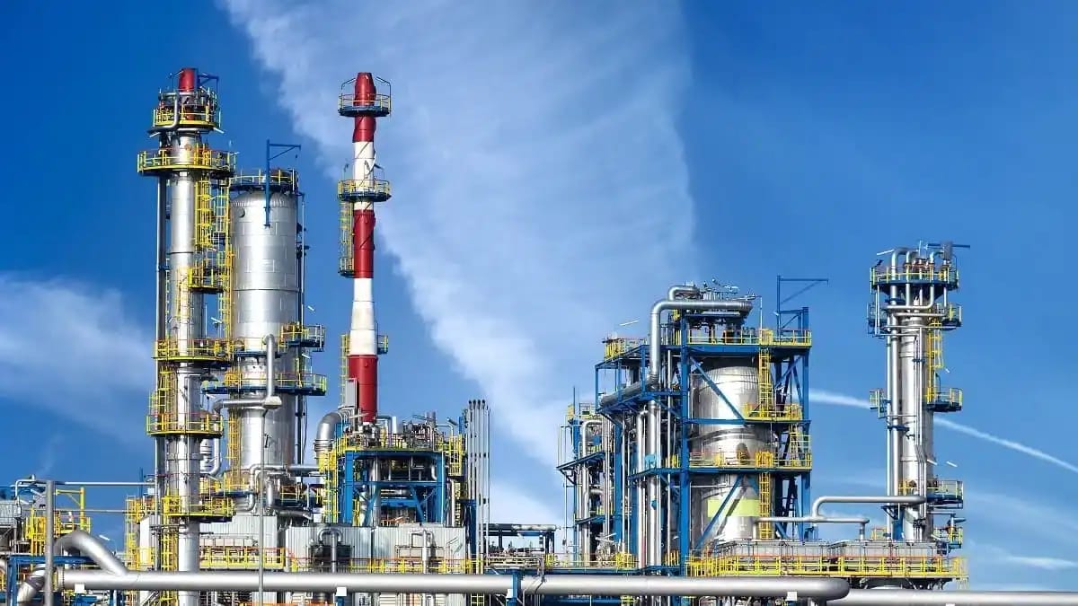 Installation pétrolière avec tours et pipelines sous ciel bleu.