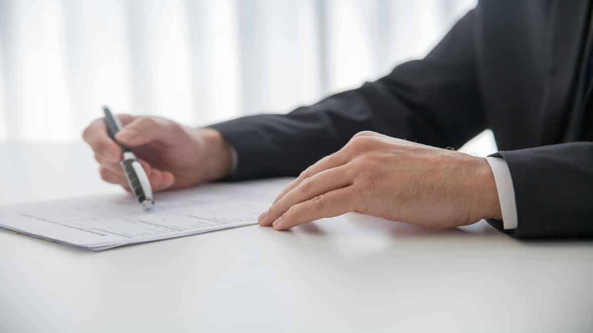 Personne signant un document officiel avec un stylo.