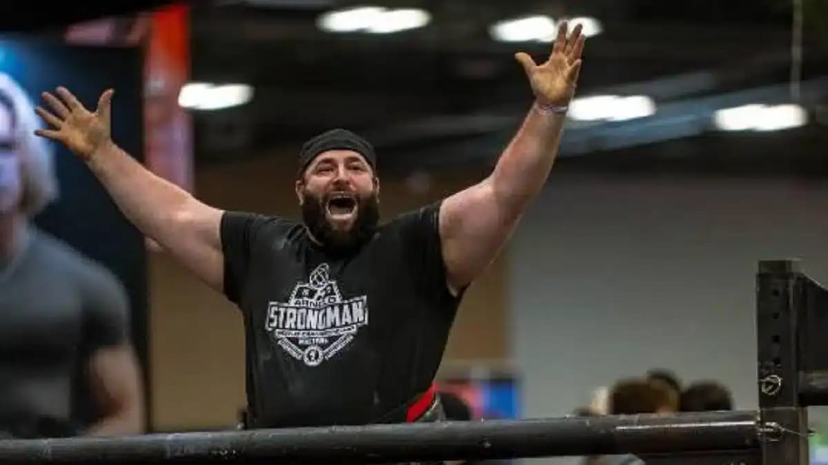 Homme musclé célébrant sa victoire en compétition de force.