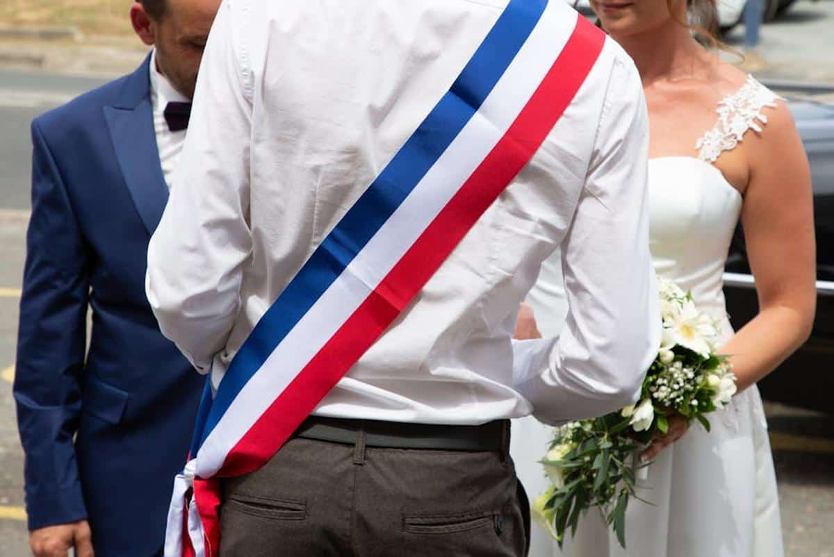 Maire en costume avec sash tricolore lors d'une cérémonie officielle.