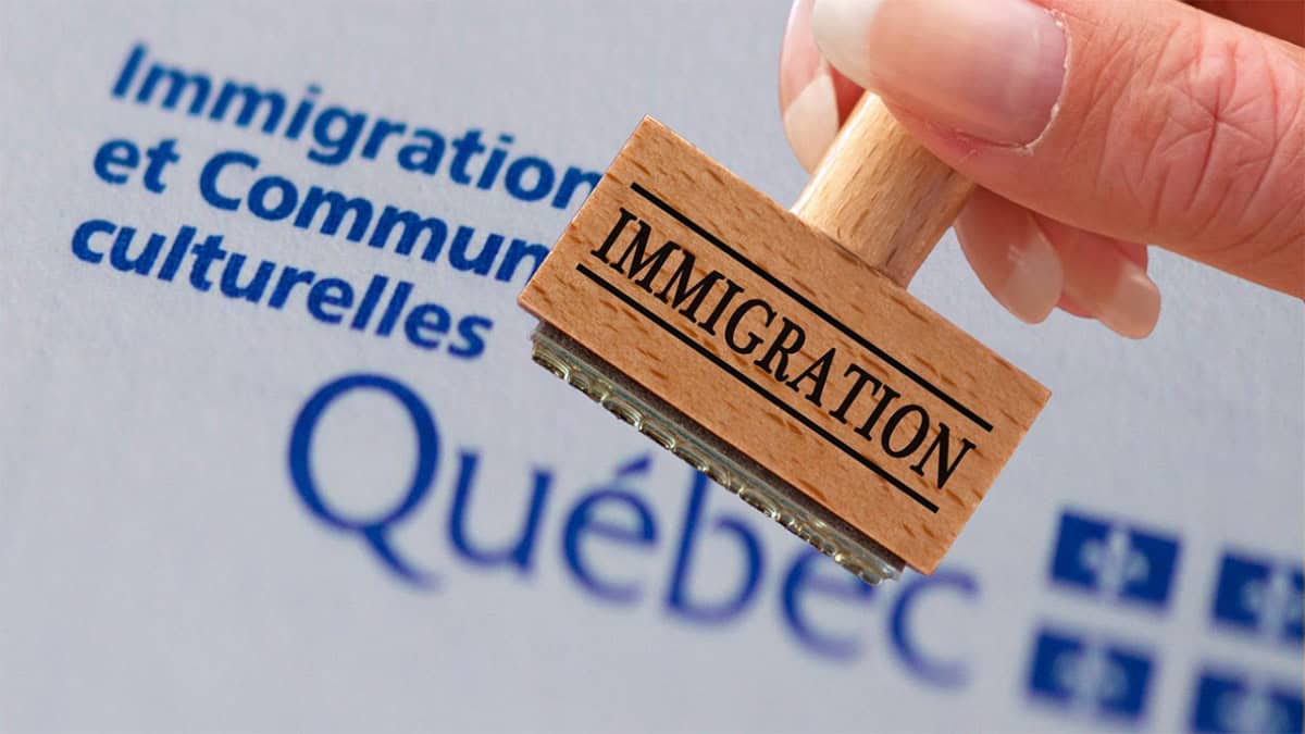Tampon en bois avec le mot 'Immigration' devant un logo du Québec.