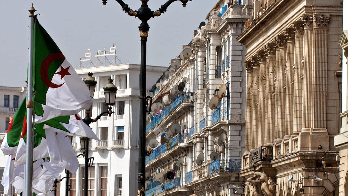 Drapeaux algériens flottant lors d'une manifestation dans une ville historique.