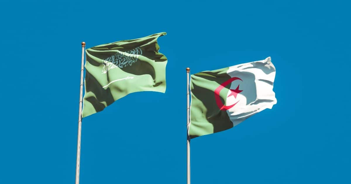 Drapeaux de l'Algérie et de l'Arabie saoudite flottant dans le ciel bleu clair.