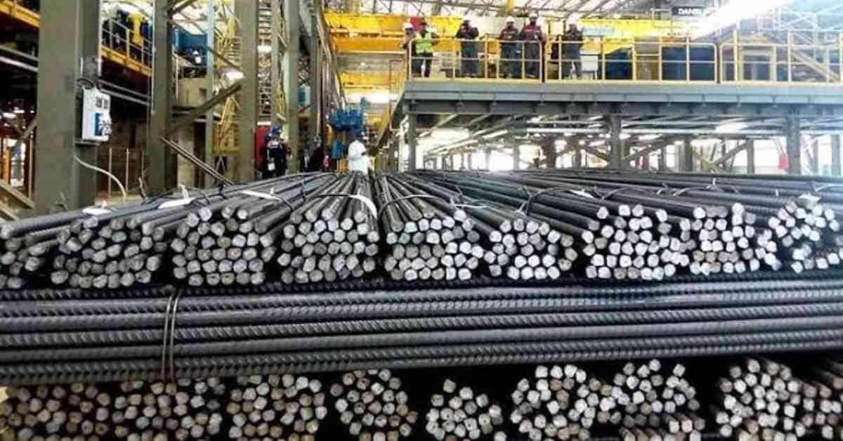 Barres d'acier dans une usine avec équipements industriels.