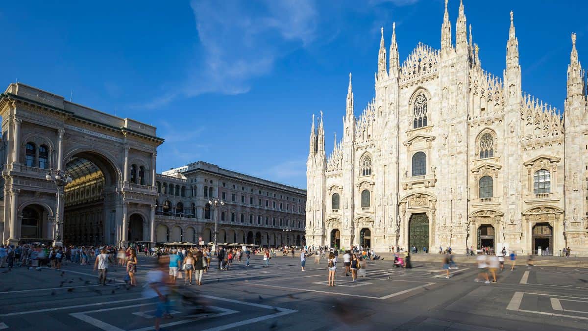 Vue de la cathédrale de Milan avec touristes et ciel bleu.