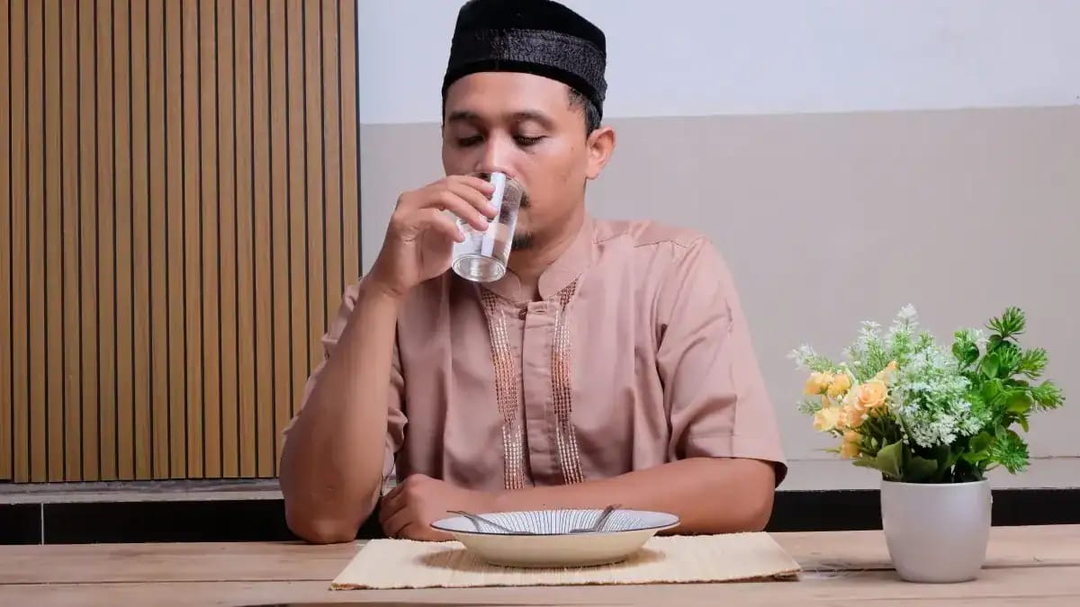 Homme buvant un verre d'eau après le jeûne du Ramadan.
