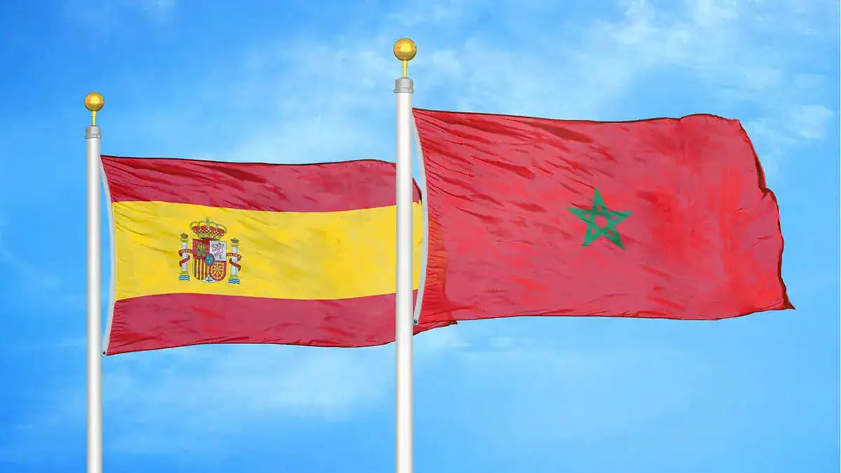 Drapeaux de l'Espagne et du Maroc flottant dans le ciel bleu.