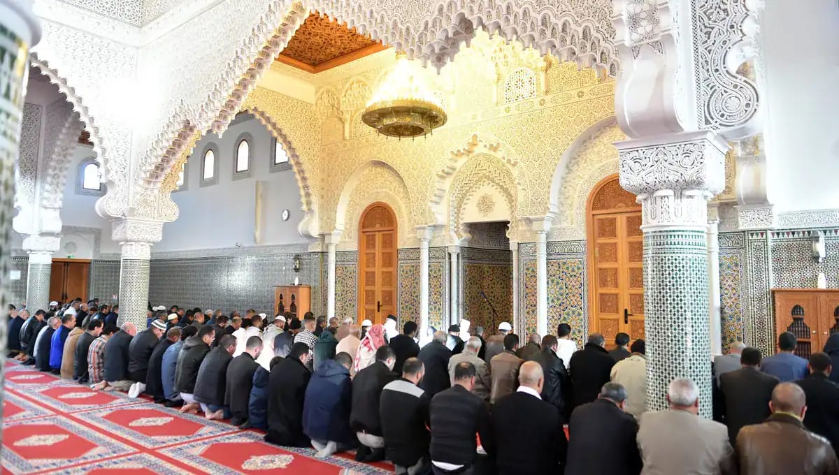 Croyants en prière dans une mosquée ornée de détails architecturaux.