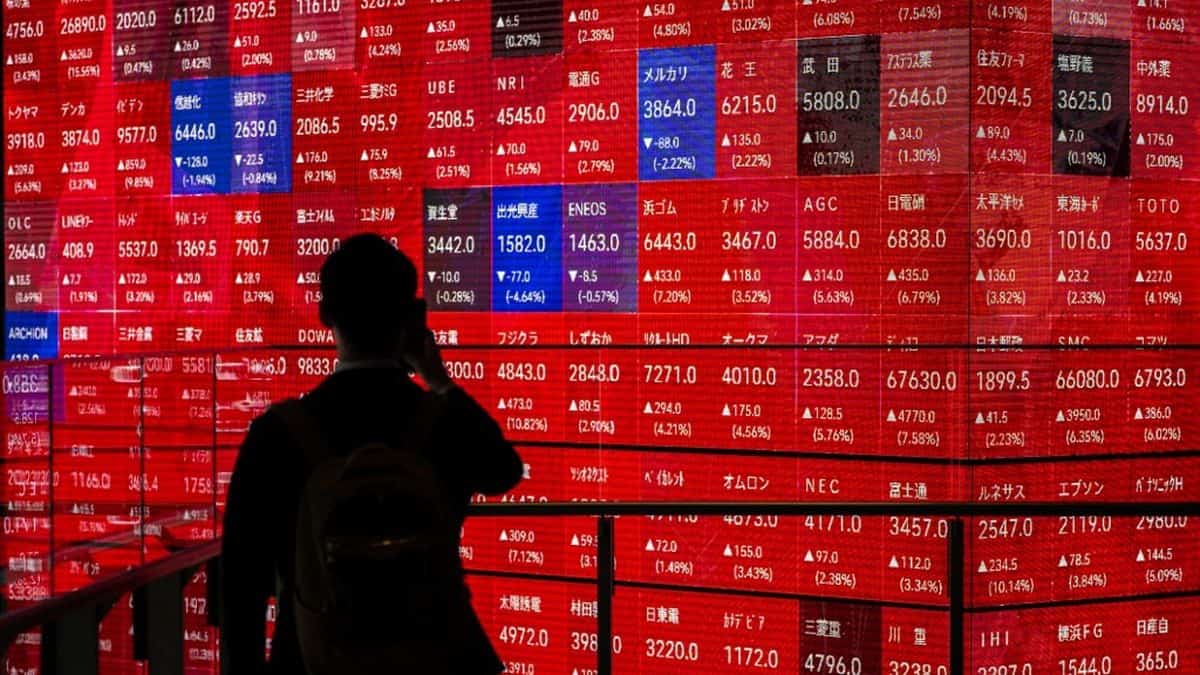 Investisseur observant un tableau boursier numérique en rouge.
