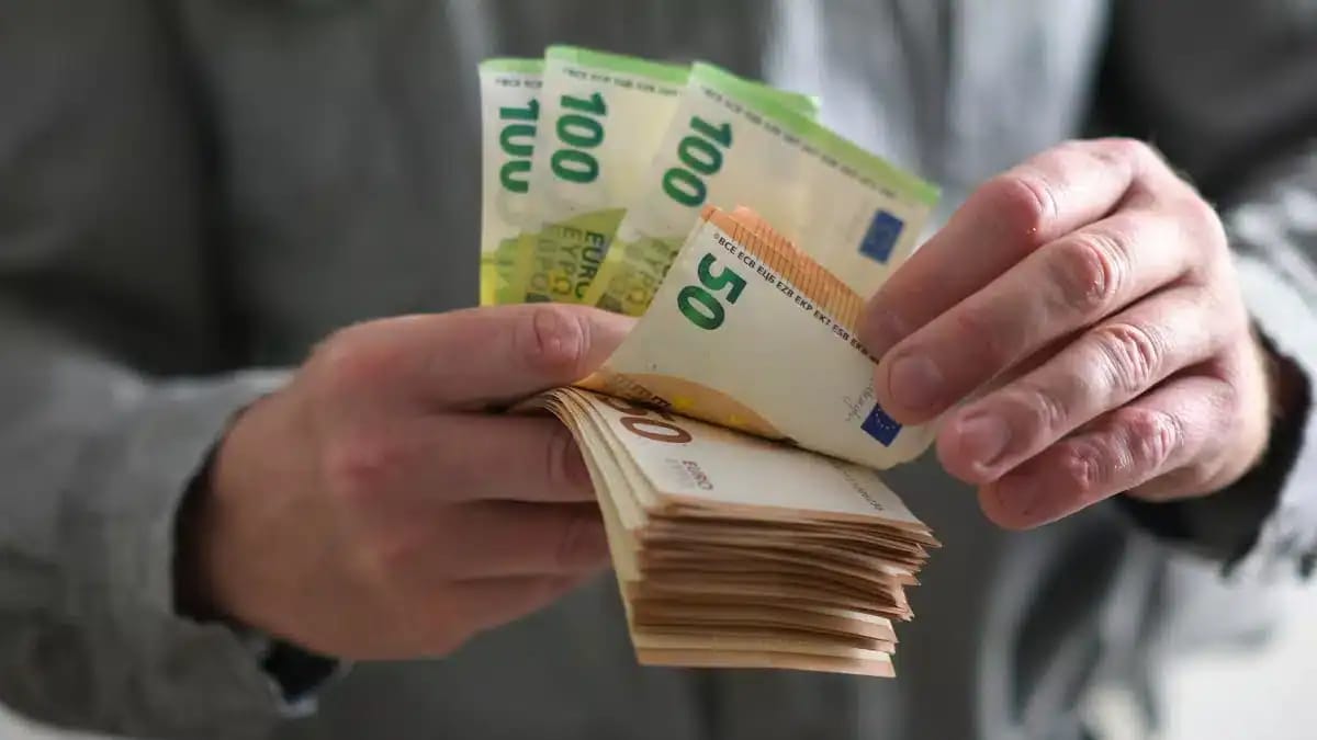 Main tenant un gros montant de billets de banque en euros.