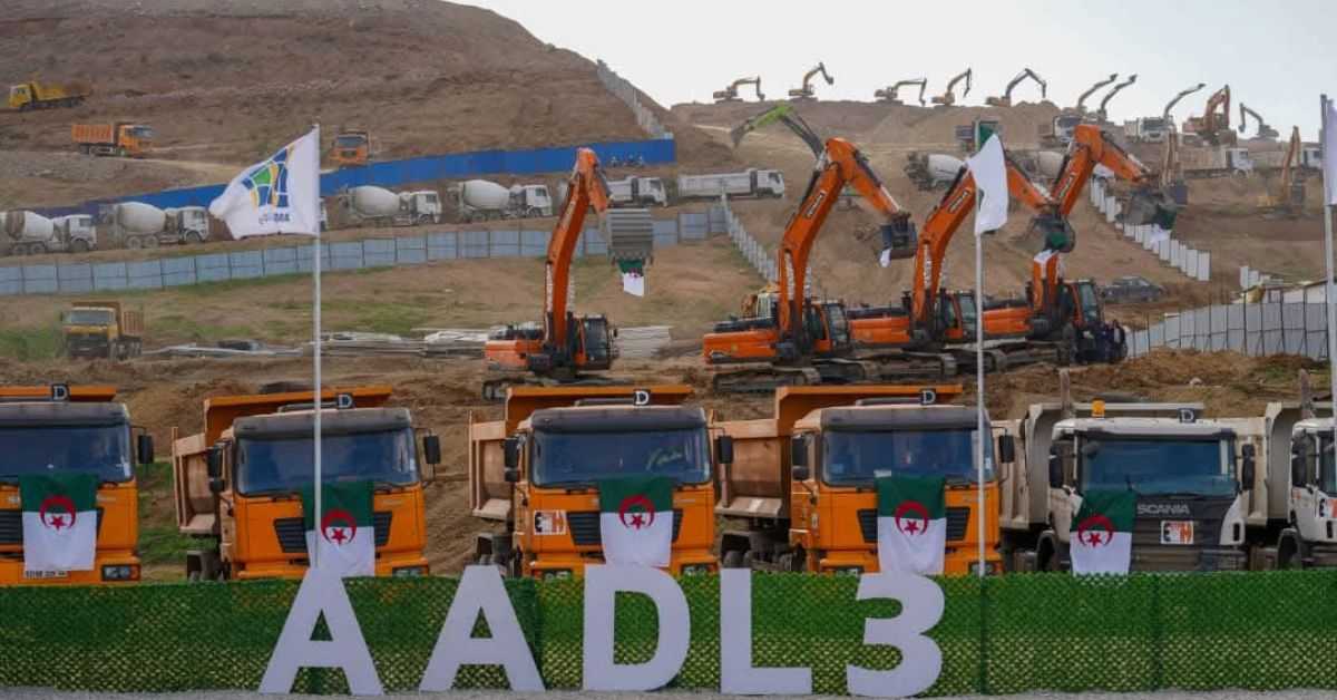 Camions de construction avec drapeaux algériens et excavatrices.