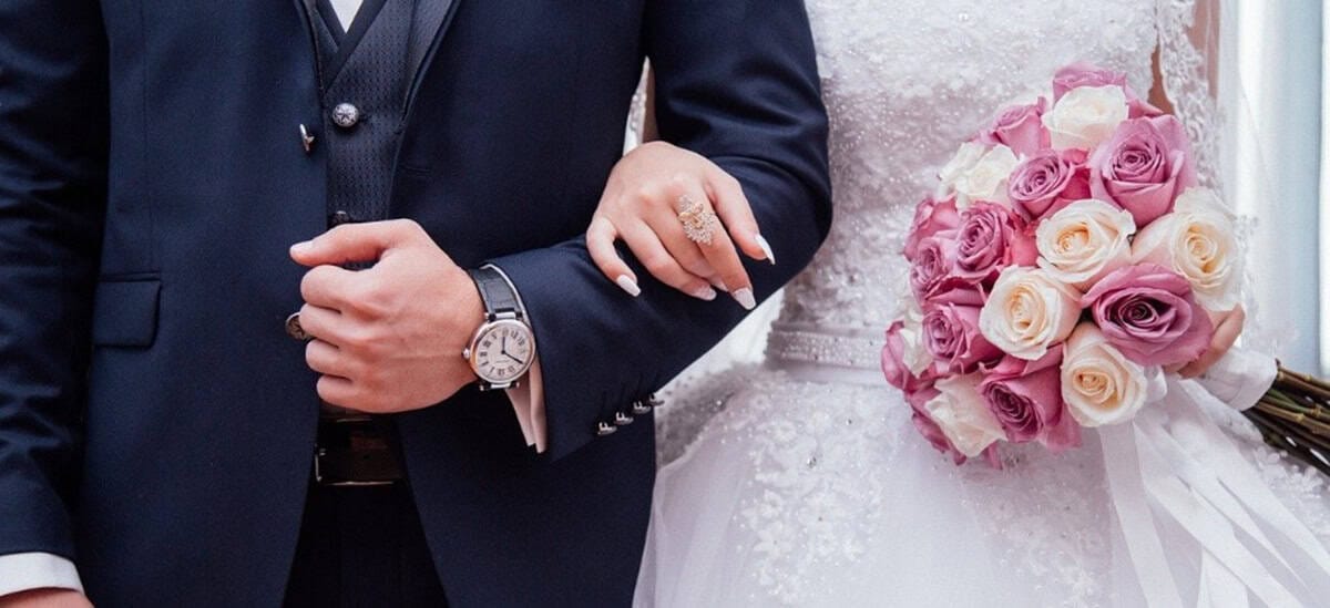 Détails d'un mariage avec un bouquet de roses et un costume élégant.
