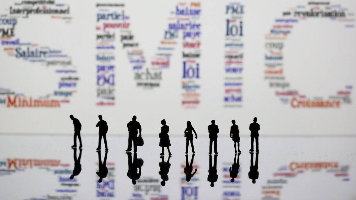 Groupe de personnes discutant devant un mur de mots liés au travail.