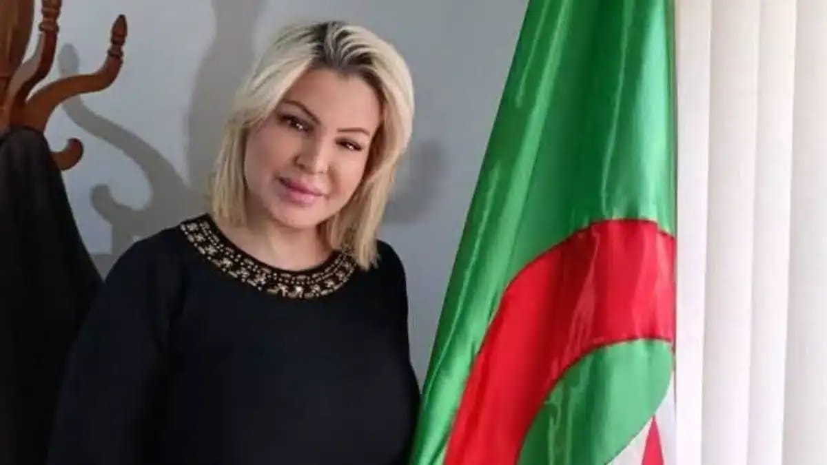Latifa Dib, ancienne avocate algérienne, posant à côté du drapeau national.