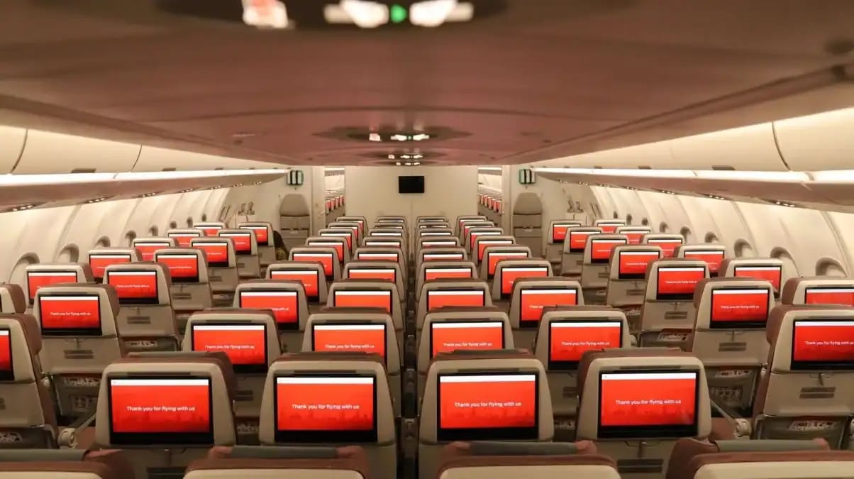 Intérieur d'un avion avec sièges et écrans de divertissement modernes.