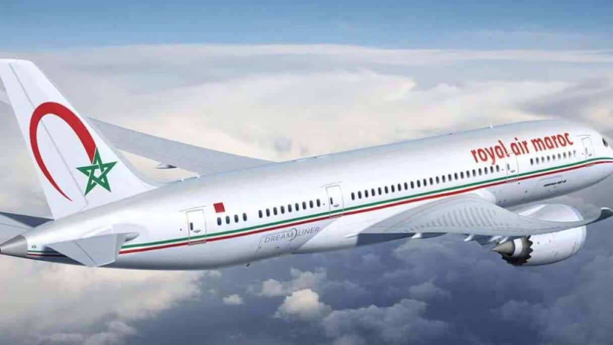 Avion Royal Air Maroc en vol, logo visible, ciel nuageux.