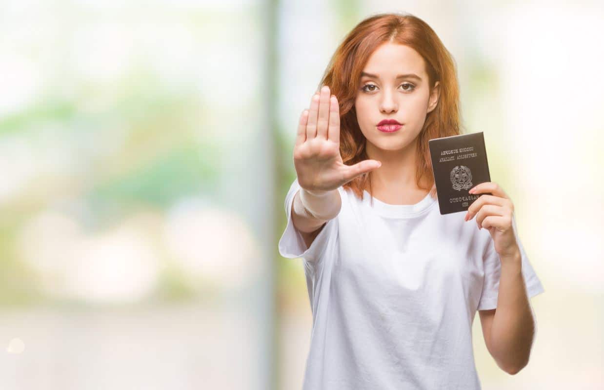 Jeune femme avec passeport et main levée pour contrôle biométrique.