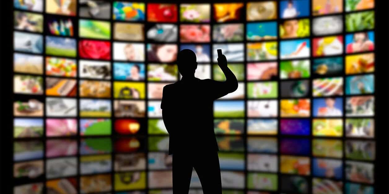 Silhouette d'un homme devant un mur d'écrans de télévision.