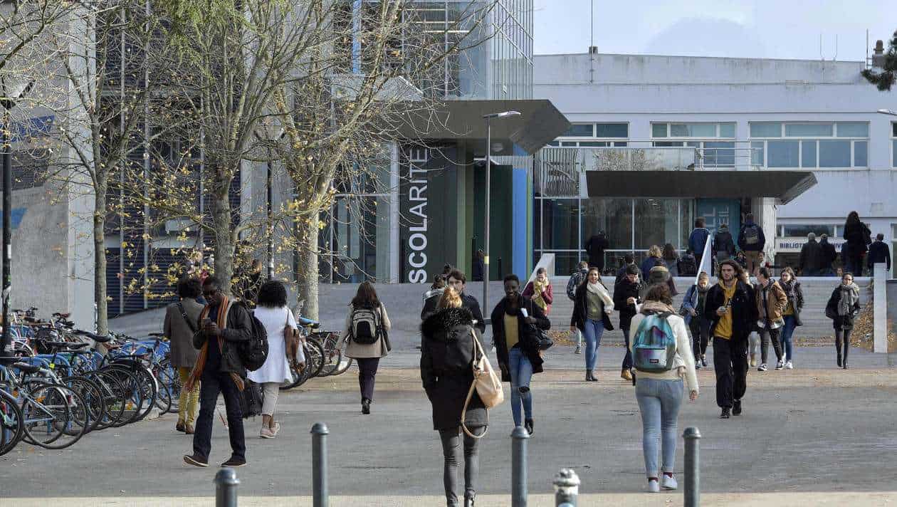 Étudiants étrangers et locaux devant une université moderne en France.