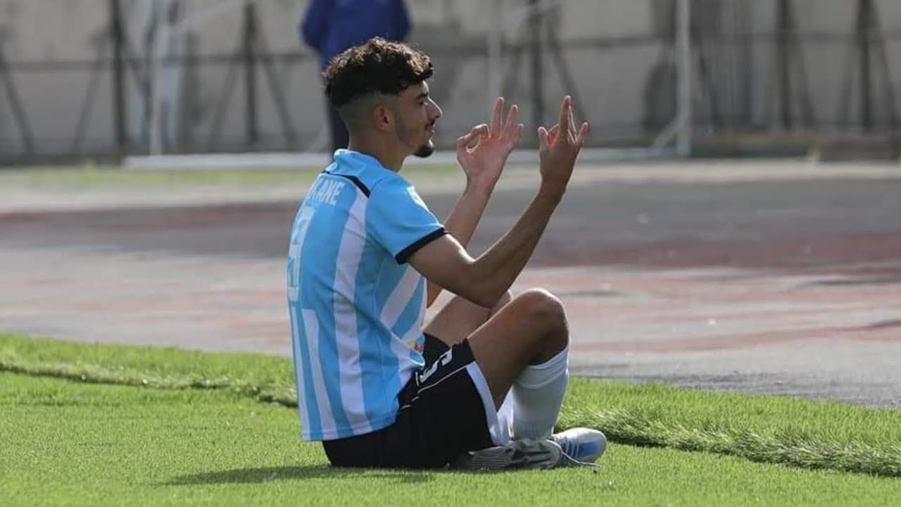 Jeune joueur de football en tenue bleue célébrant sur le terrain.
