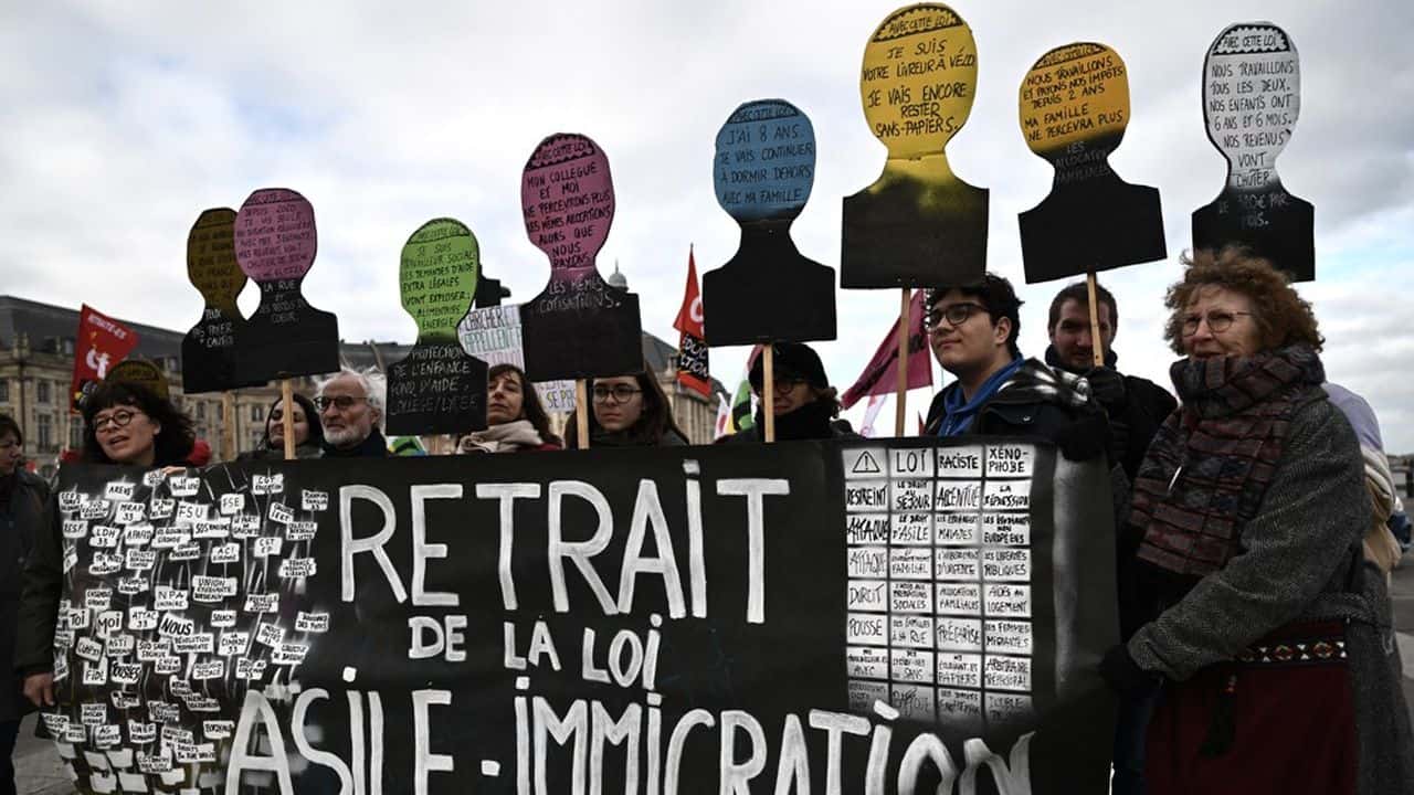 Manifestants avec pancartes et silhouettes symboliques pour la régularisation.