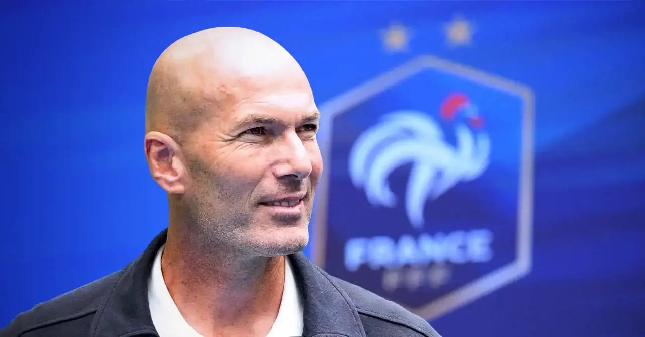 Zinedine Zidane lors d'une conférence, fond bleu avec logo France.