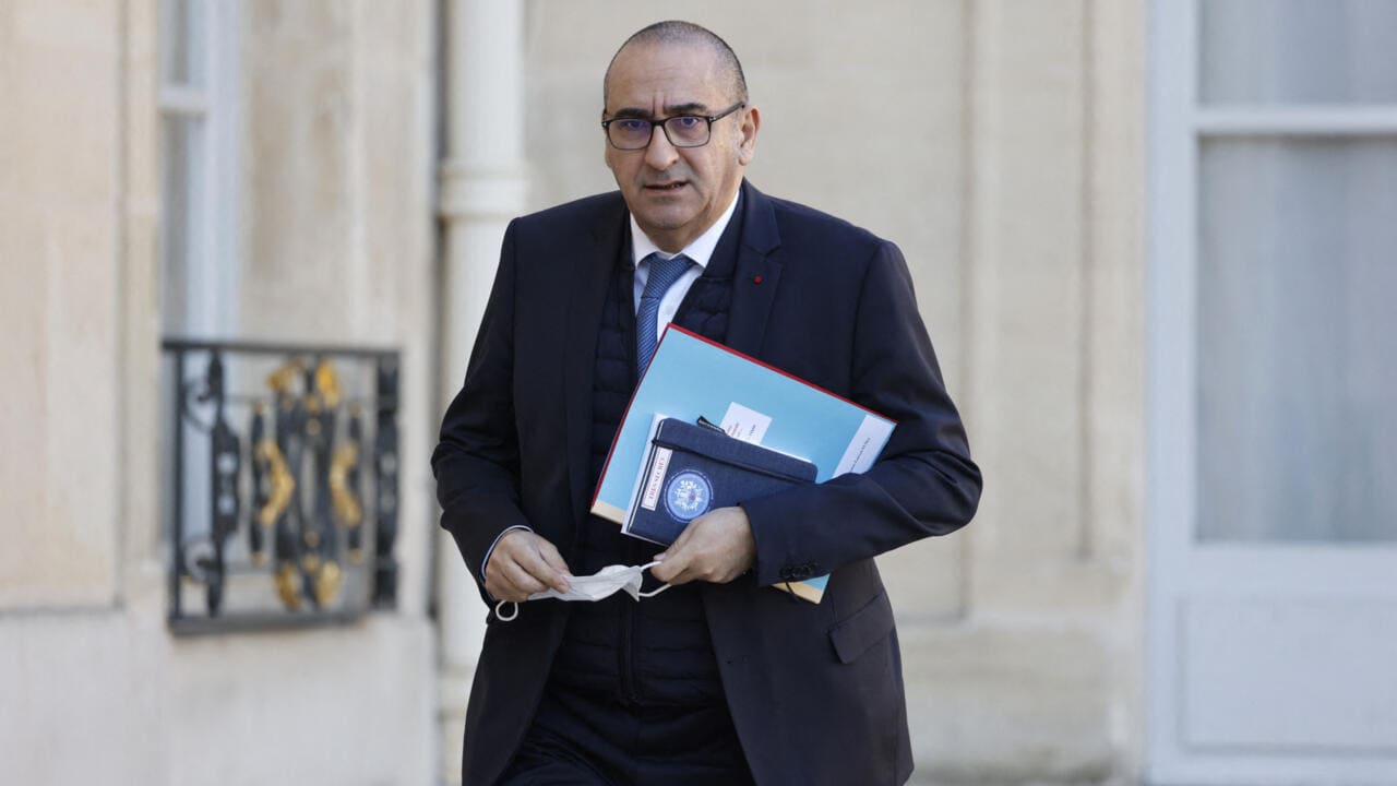 Homme en costume avec documents à Alger, progrès en immigration.