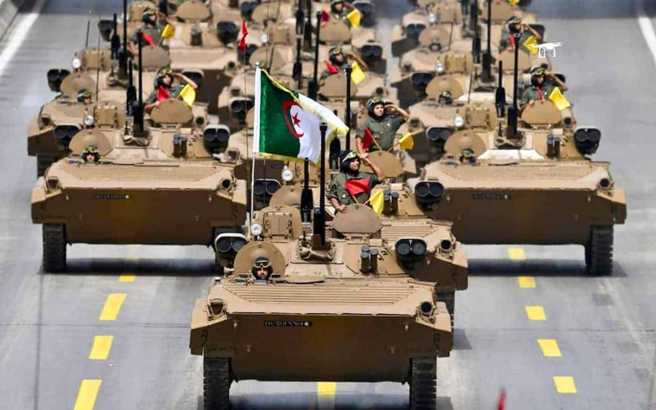 Véhicules militaires en formation avec drapeau algérien.