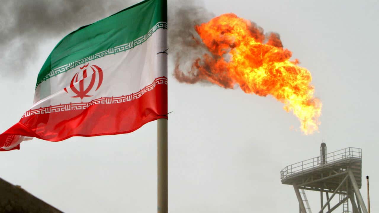 Drapeau iranien et flamme de gaz en feu sur plateforme pétrolière.