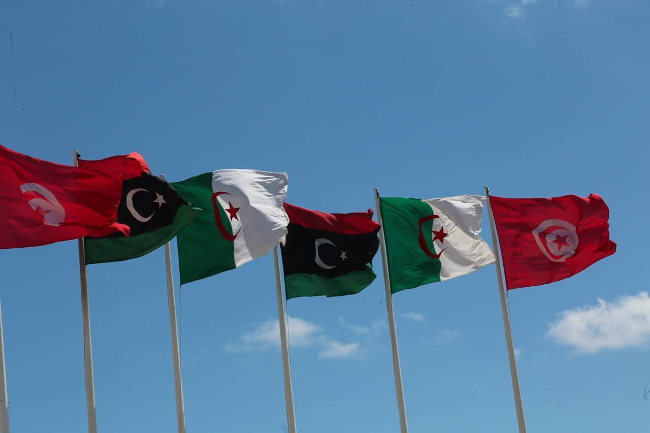 Drapeaux du Maghreb flottant sous un ciel bleu clair.