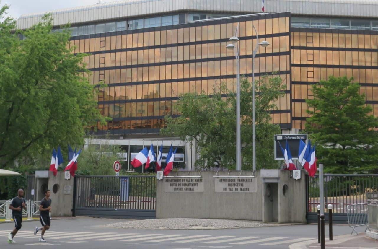 Préfecture avec drapeaux français et bâtiment moderne en arrière-plan.