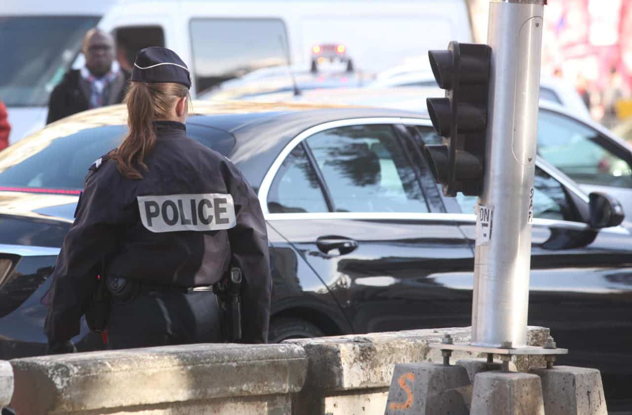 Policière en uniforme à côté d'une voiture noire en ville.