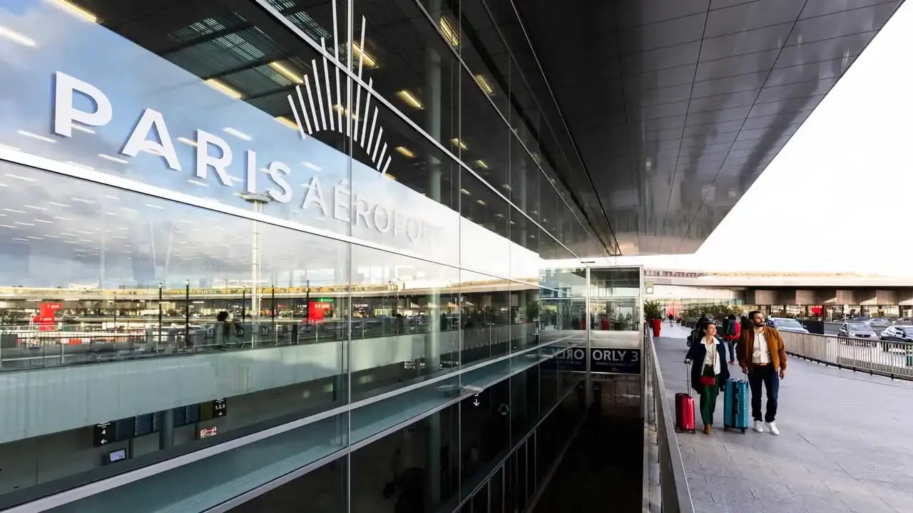 Voyageurs à l'aéroport Paris avec valises et terminal moderne.