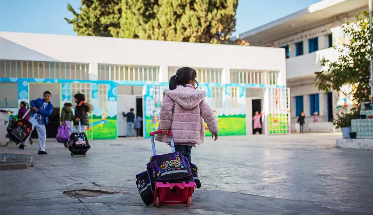 Enfants quittant l'école avec leurs sacs à dos colorés.