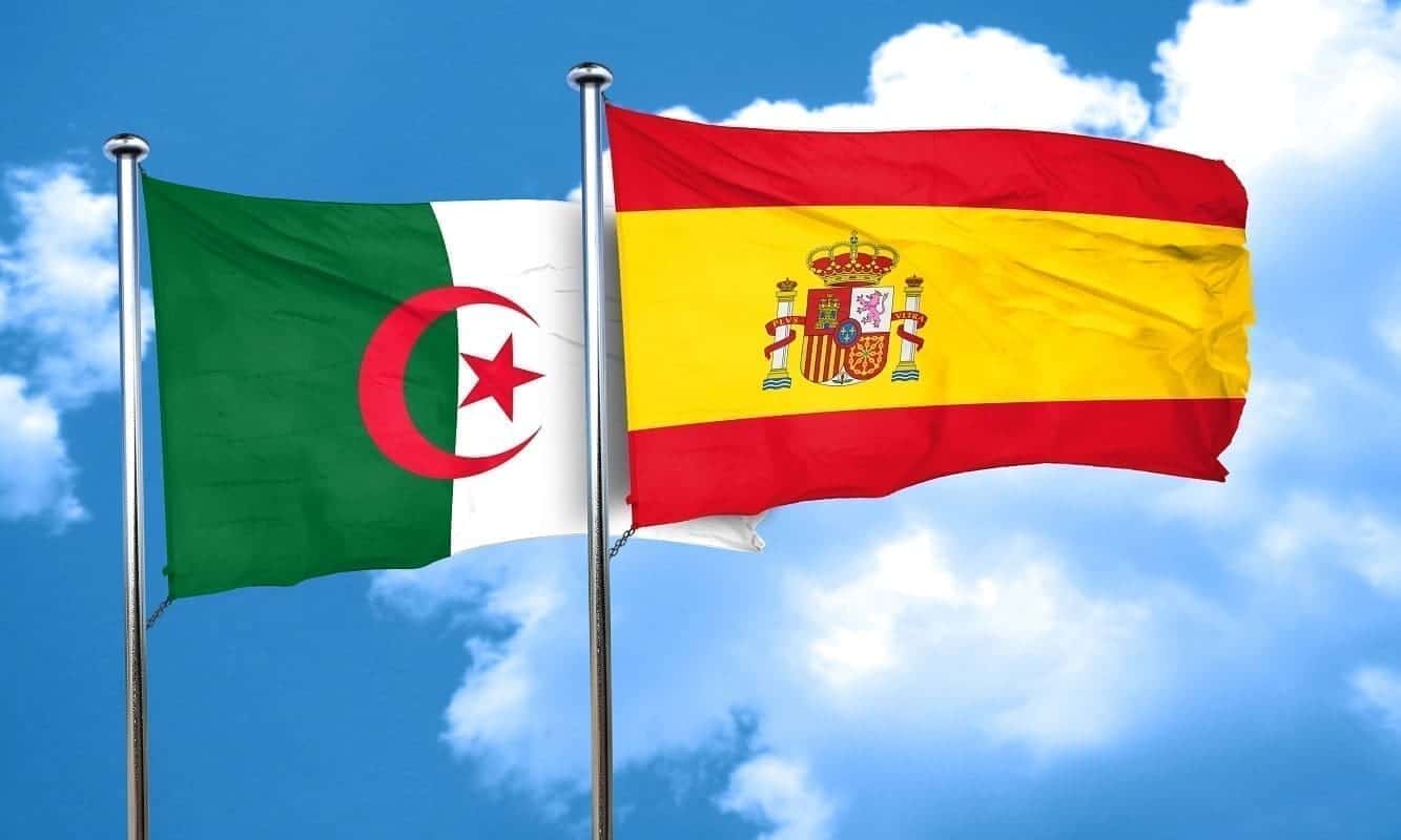 Drapeaux d'Algérie et d'Espagne flottant dans le ciel bleu.