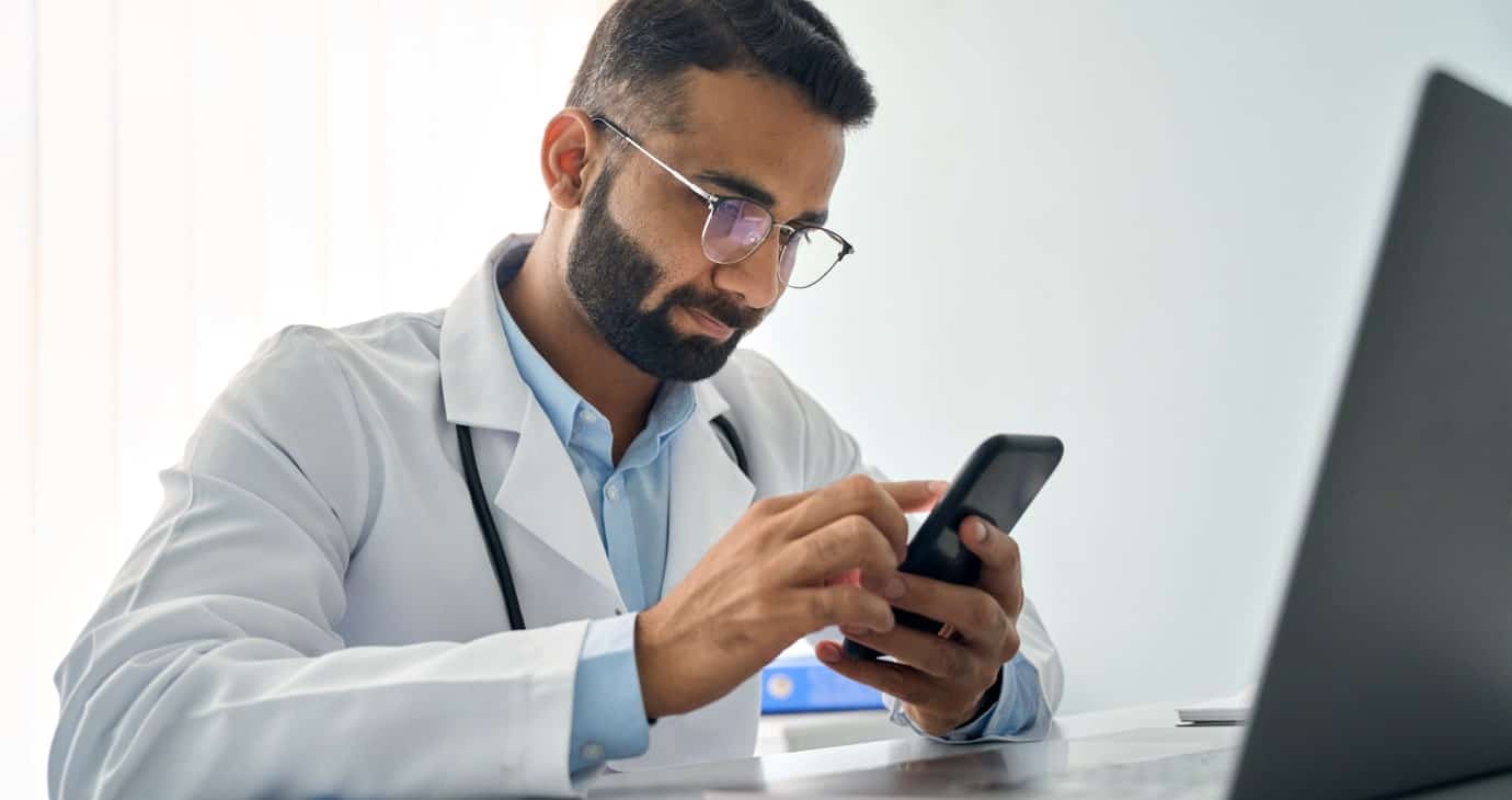 Médecin professionnel utilisant un smartphone dans un bureau moderne.