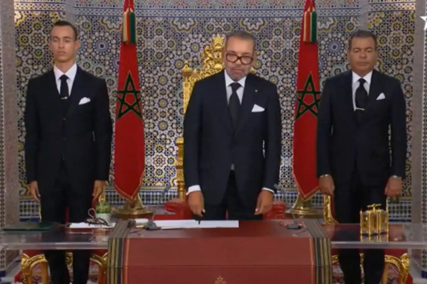 Trois hommes en costume lors d'une cérémonie royale au Maroc.