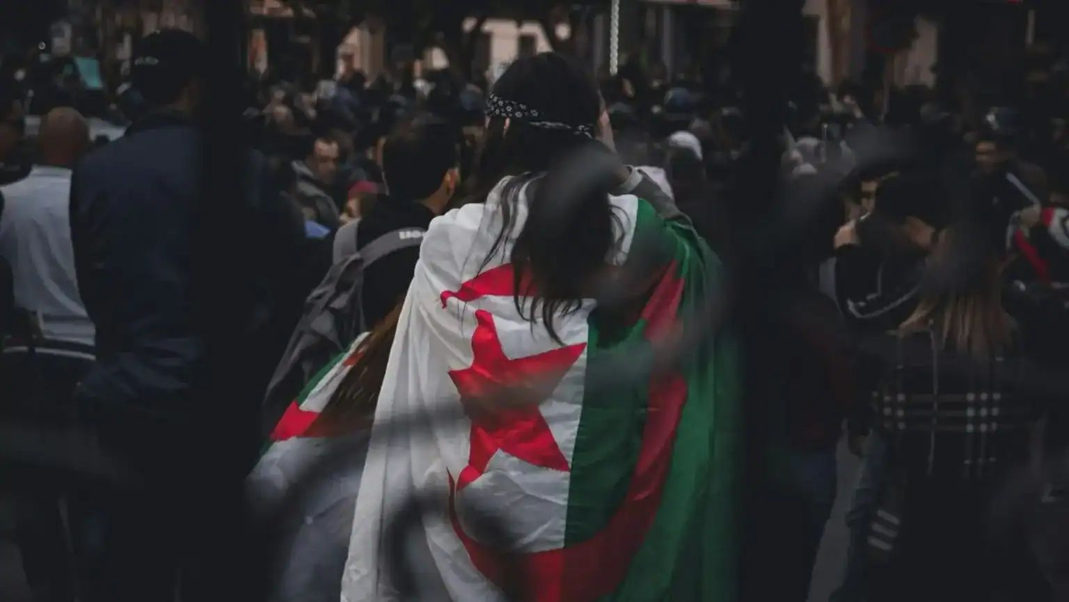 Migrants en Espagne avec drapeau algérien, protestation et défi.
