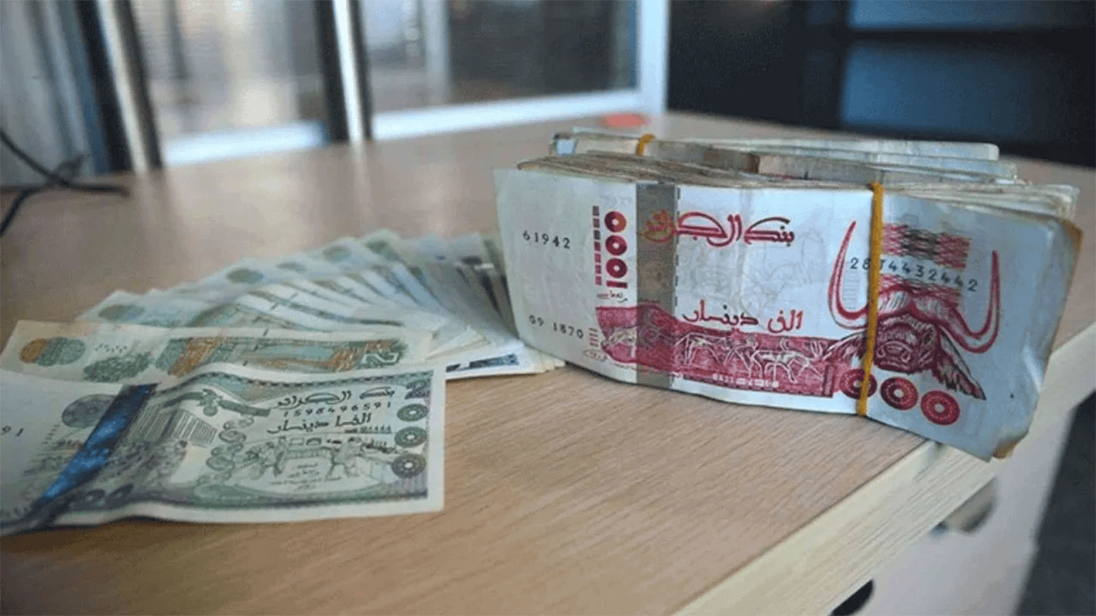 Faux billets de banque algériens empilés sur une table.