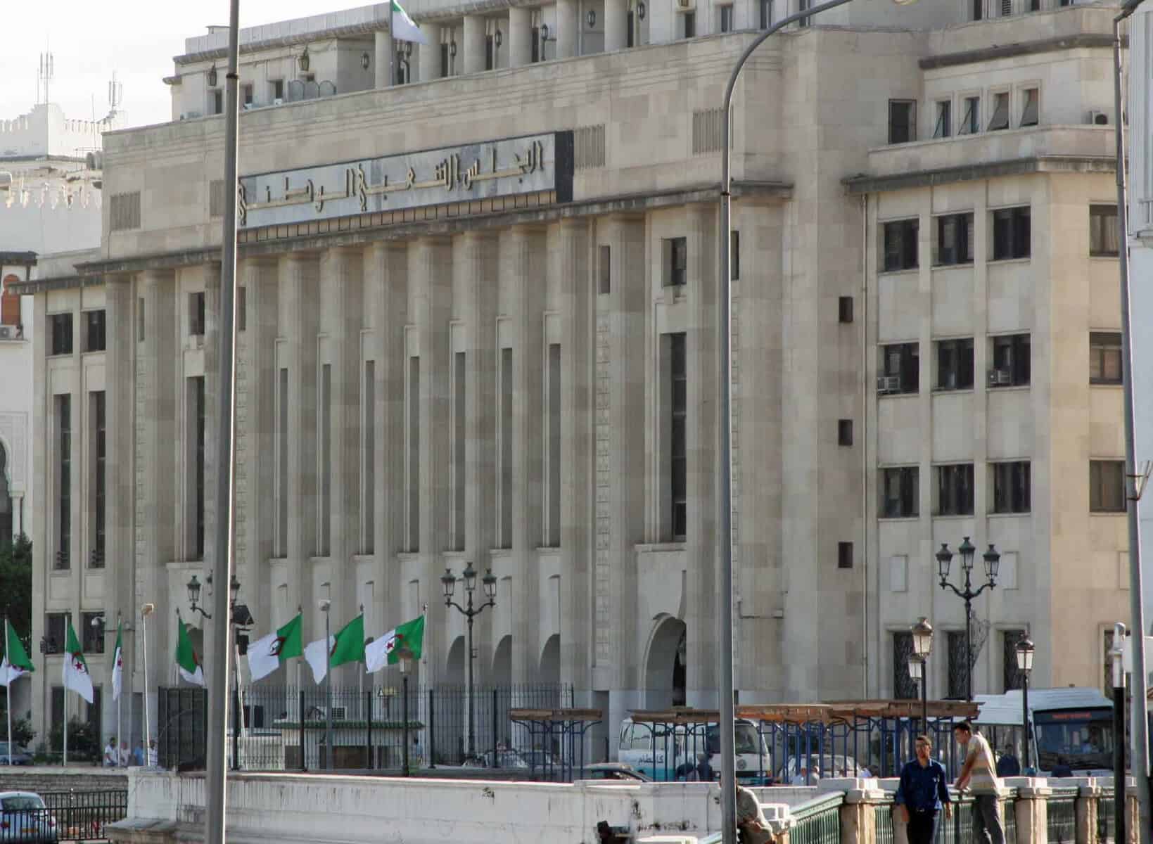 Façade d'un bâtiment gouvernemental en Algérie avec drapeaux.